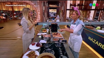 Dos mujeres conversan frente a una mesada con ingredientes y utensilios en una cocina de estudio televisivo