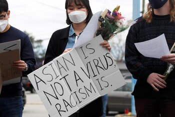 Una chica con un cartel que dice: "Los asiáticos no son un virus, el racismo si lo es"