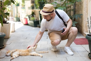 Un hombre acariciando un gato en la calle. (Freepik)