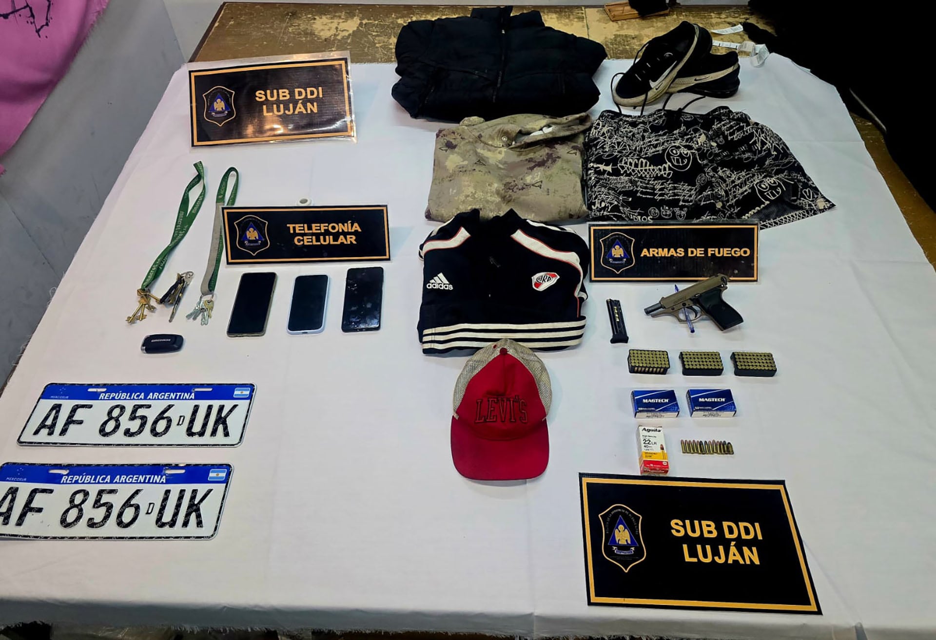 Elementos incautados a los delincuentes que robaron una casa y tomaron a una mujer como rehén en Luján, incluyendo armas, celulares y placas de vehículos.