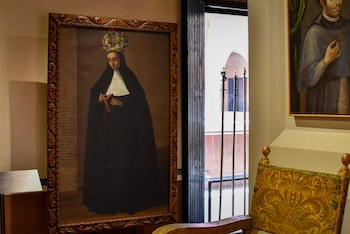 Óleo enmarcado de una monja coronada con hábito negro y tocado floral, sosteniendo un libro y un rosario, expuesto en una sala del Museo Regional de Tlaxcala