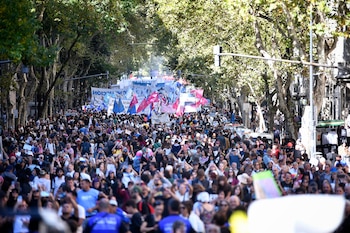 Gran multitud de personas visible en una avenida arbolada. Al fondo se distinguen numerosas pancartas y banderas, mientras algunos levantan sus brazos