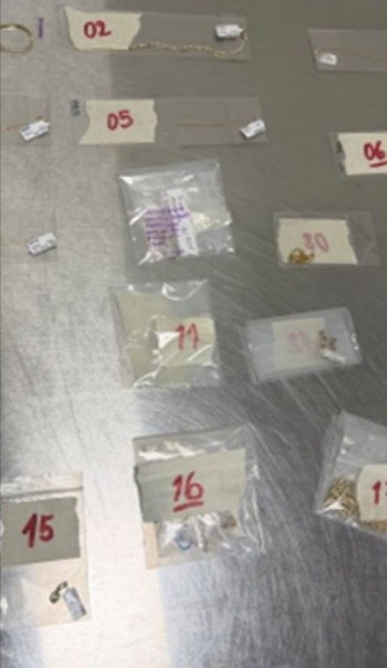 Bolsas plásticas transparentes numeradas con piezas de joyería dorada sobre una mesa metálica