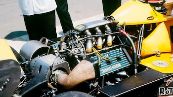 Vista de cerca de un motor Renault Gordini expuesto en un auto de carreras amarillo, con componentes mecánicos y tuberías visibles