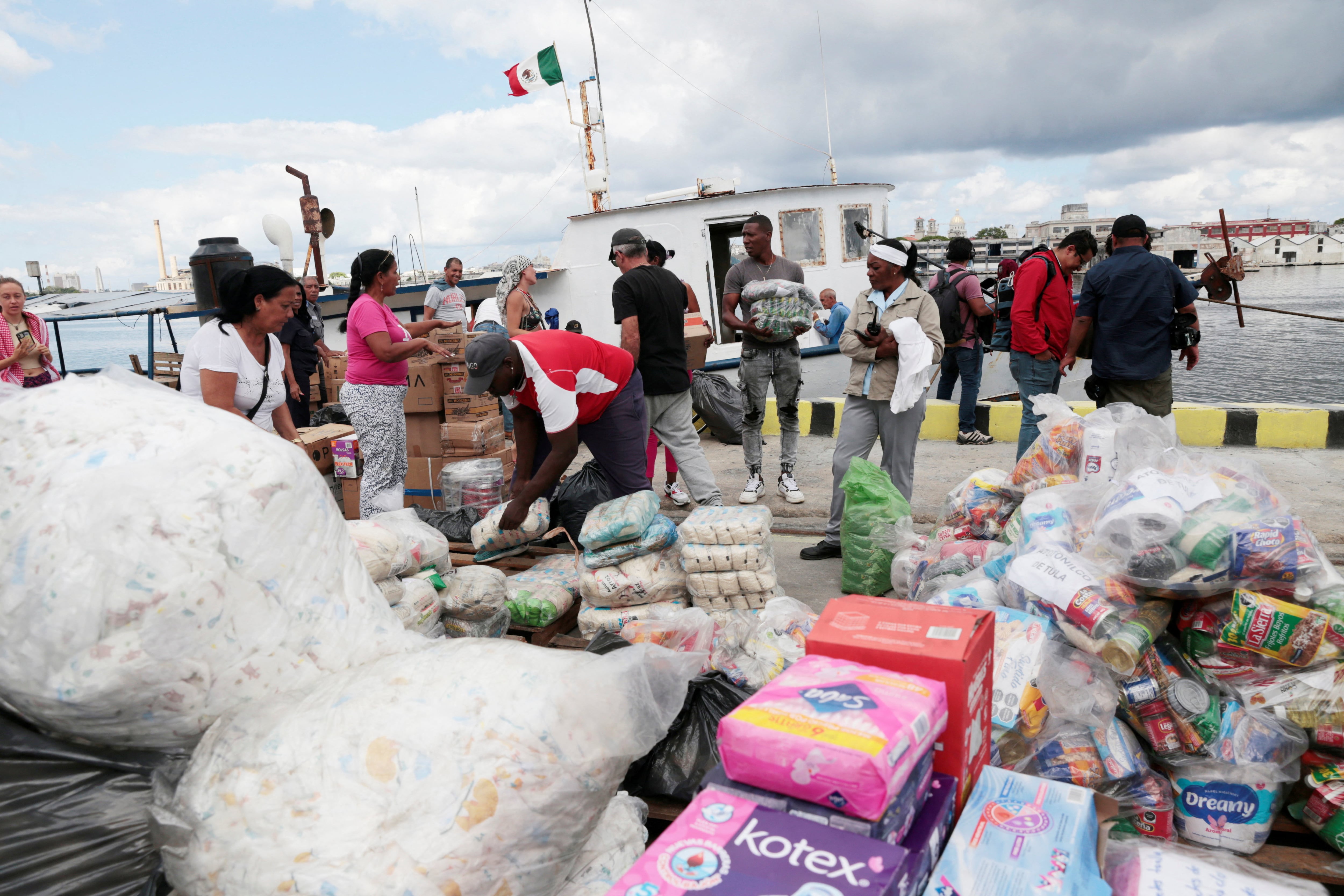 Miembros de una flotilla que partió de México, junto con trabajadores portuarios locales, descargan ayuda humanitaria a su llegada a la bahía de La Habana en medio de un bloqueo petrolero estadounidense que ha asestado un duro golpe a la ya precaria infraestructura energética de la isla, en La Habana, Cuba, el 24 de marzo de 2026. Jorge Luis Baños/Pool vía REUTERS