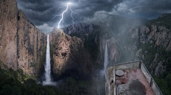 Cielo oscuro con lluvia y rayo sobre montañas con una cascada y una plataforma de observación en primer plano.