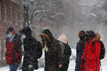 Pedestrians walk through falling snow
