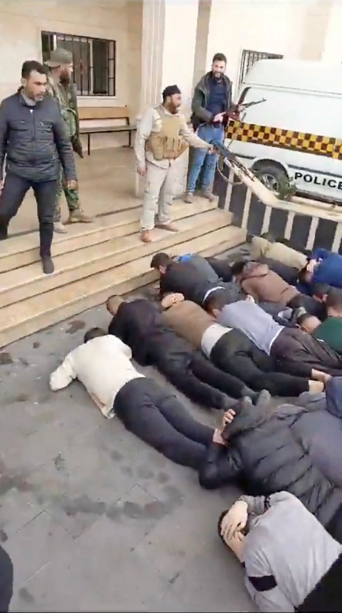 Combatientes observan a los alauitas sirios que fueron obligados a permanecer en el suelo en Salhab, Siria, en esta captura de pantalla de un video publicado en las redes sociales y verificado por Reuters. (Reuters)
