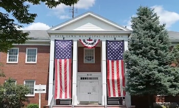 Edificio municipal de ladrillo rojo con dos banderas de Estados Unidos en la fachada y un cartel superior que lee "Fair Lawn Municipal Building"