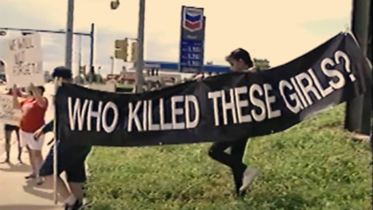 Manifestantes sostienen una gran pancarta negra con la pregunta