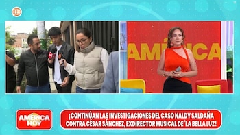 Pantalla de televisión dividida. Izquierda: un hombre entrevistado por reporteros y una mujer con gafas. Derecha: una presentadora en un estudio. Banner con texto