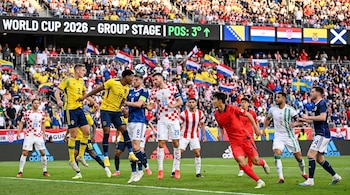 Jugadores de ocho selecciones nacionales de fútbol disputan un balón en un estadio. Marcador digital: "World Cup 2026" y "POS: 3° ^". Hinchas.