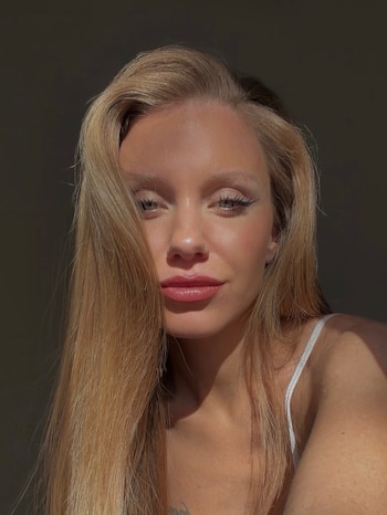 Retrato de Rocío Pardo, mujer de cabello largo rubio, iluminada por luz solar sobre un fondo oscuro