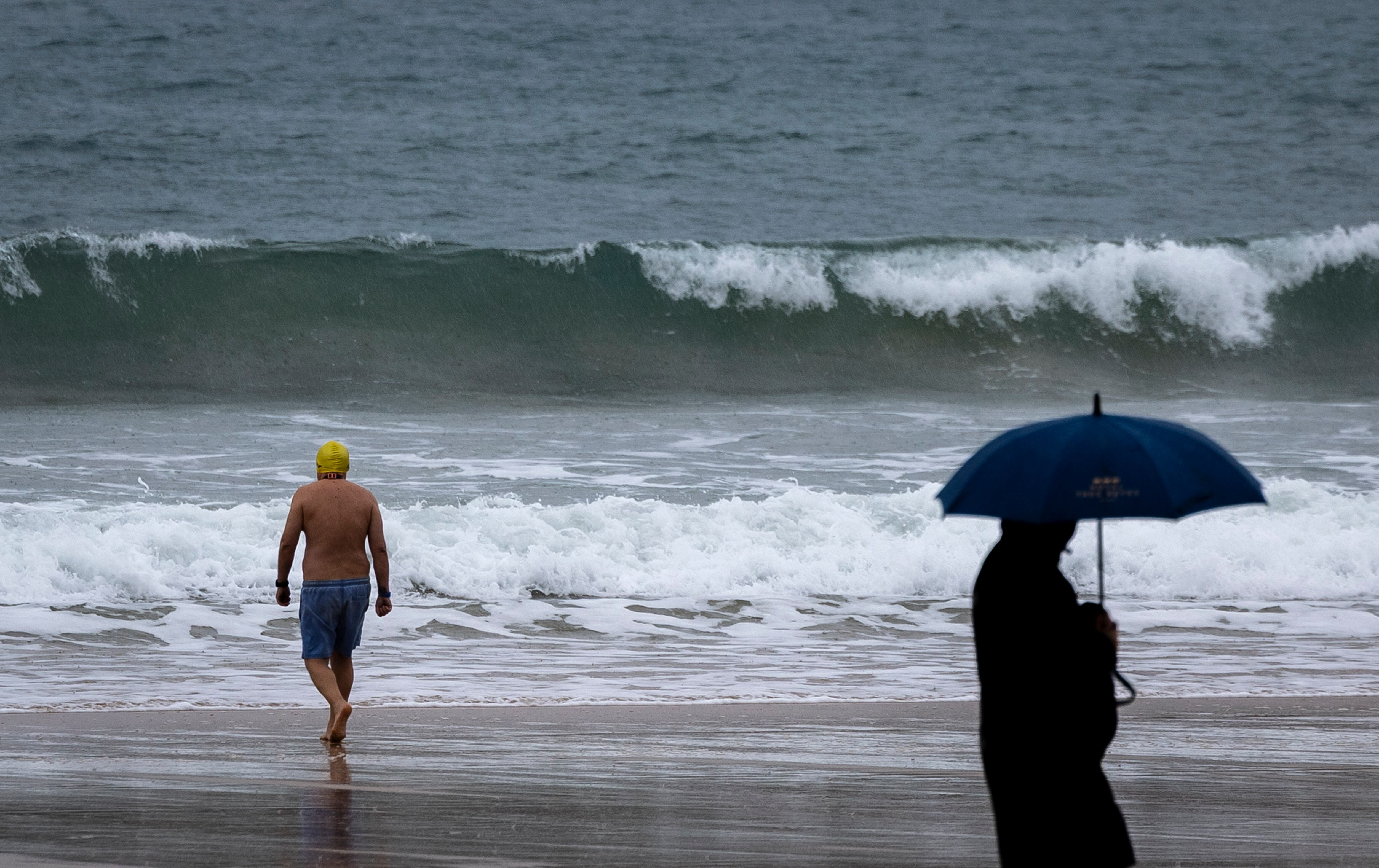 Un bañista se mete al agua en la playa de La Concha de San Sebastián a pesar del tiempo adverso, a 24 de noviembre de 2025. (EFE/Javier Etxezarreta)