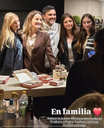 Fabián Cubero y Mica Viciconte sonriendo, rodeados por tres jóvenes rubias y morenas, frente a una mesa con un pastel y cajas de postres