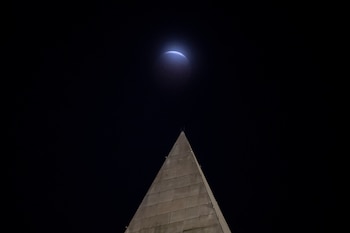Se observa un eclipse lunar a través de las nubes, detrás del Monumento a Washington, en Washington, el viernes 28 de agosto de 2026 (AP/Cliff Owen)