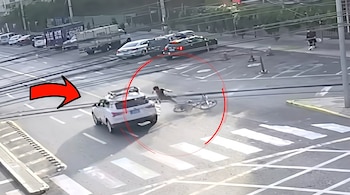 Vista aérea de una intersección donde una camioneta blanca choca a una persona, señalado por un círculo y una flecha rojos