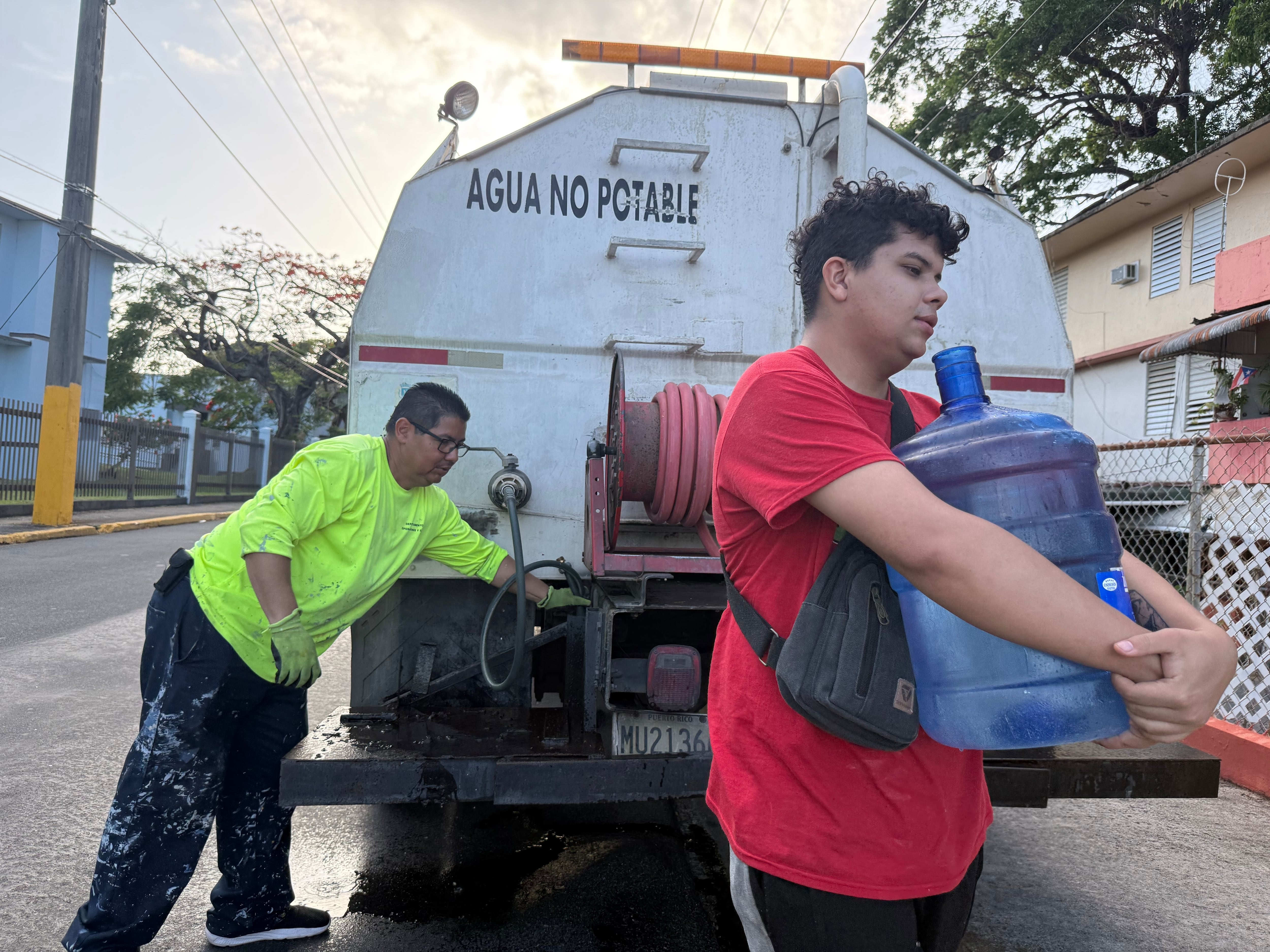 Bryan Pérez carga con una garrafa de agua para su departamento en el complejo de viviendas públicas Villa Kennedy, en San Juan, Puerto Rico, el 10 de junio de 2026. / AP Foto - Dánica Coto