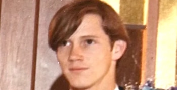 Primer plano de un joven con cabello castaño claro peinado hacia un lado, tez clara y mirada fija, sobre un fondo borroso de tonos cálidos