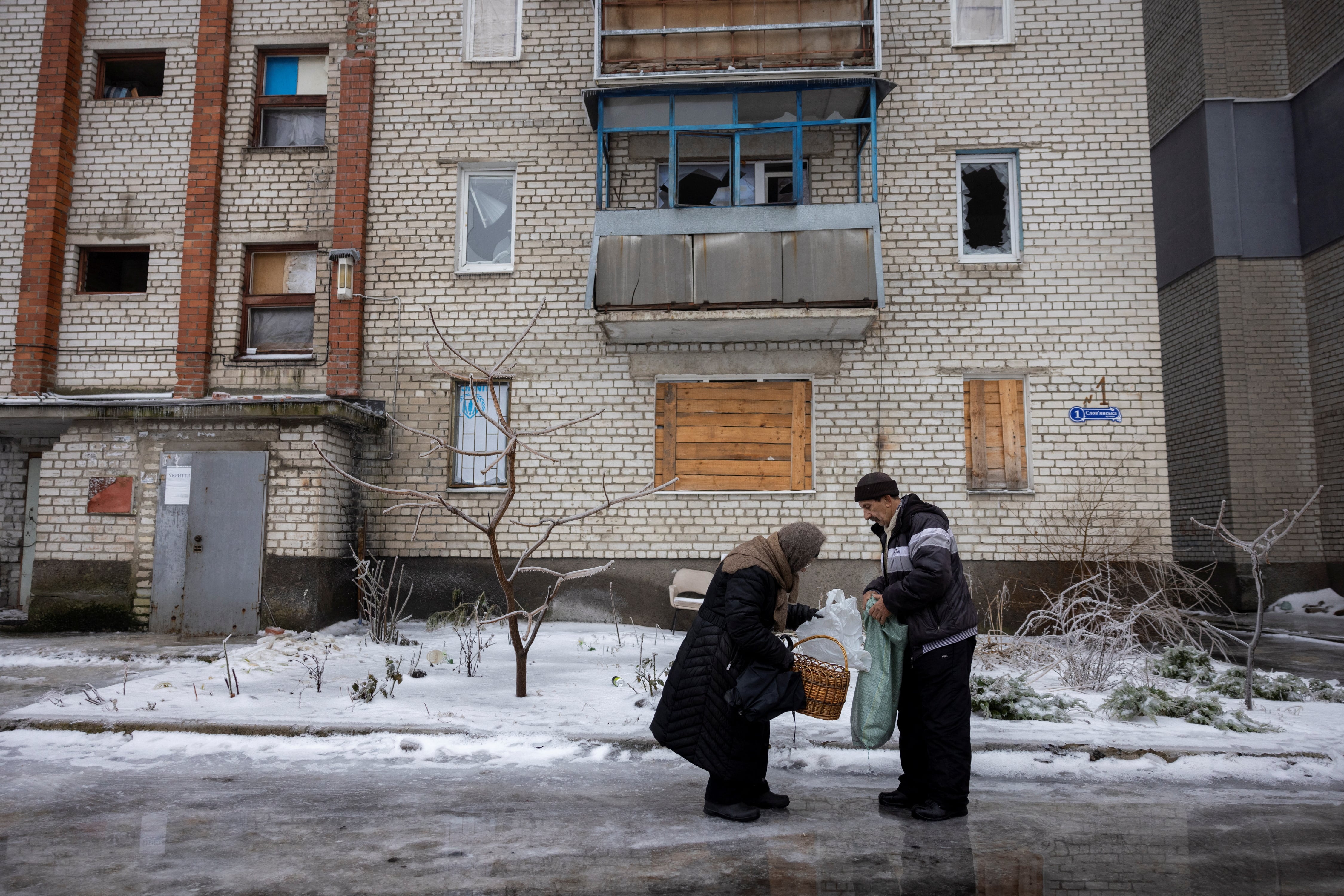 Un conductor entrega comestibles a una mujer que es una de las pocas residentes que quedan en un vecindario que resultó gravemente dañado por los combates en la ciudad fronteriza de Lyman, en medio del ataque de Rusia a Ucrania (REUTERS/Thomas Peter)