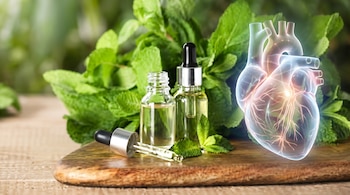 Enfoque en dos botellas de aceite esencial sobre una tabla de madera, rodeadas de hojas de menta fresca, con una representación translúcida del corazón humano.