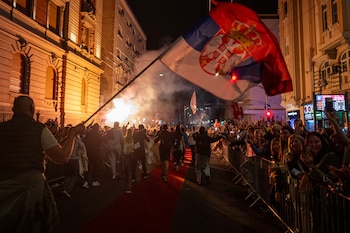Estudiantes ondean una gigantesca bandera serbia mientras son recibidos por los vecinos a su llegada al centro de Belgrado el 21 de octubre de 2026 (ANDREJ ISAKOVIC / AFP)