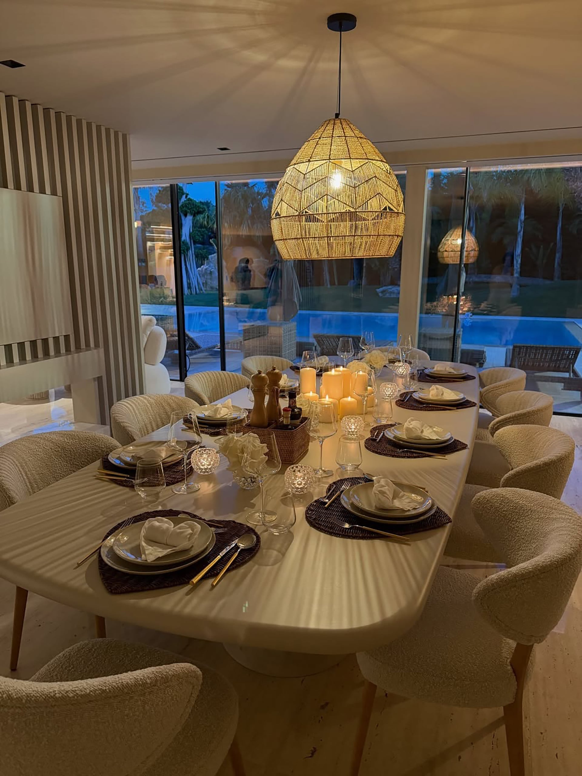 El elegante comedor de la mansión de Cristiano Ronaldo, preparado para una cena, ofrece una vista nocturna de su piscina y exuberantes exteriores.