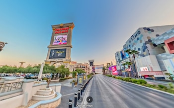 Una calle flanqueada por edificios de hoteles y casinos, con el letrero 'Caesars Palace' a la izquierda y el edificio 'The LINQ' a la derecha, bajo un cielo claro