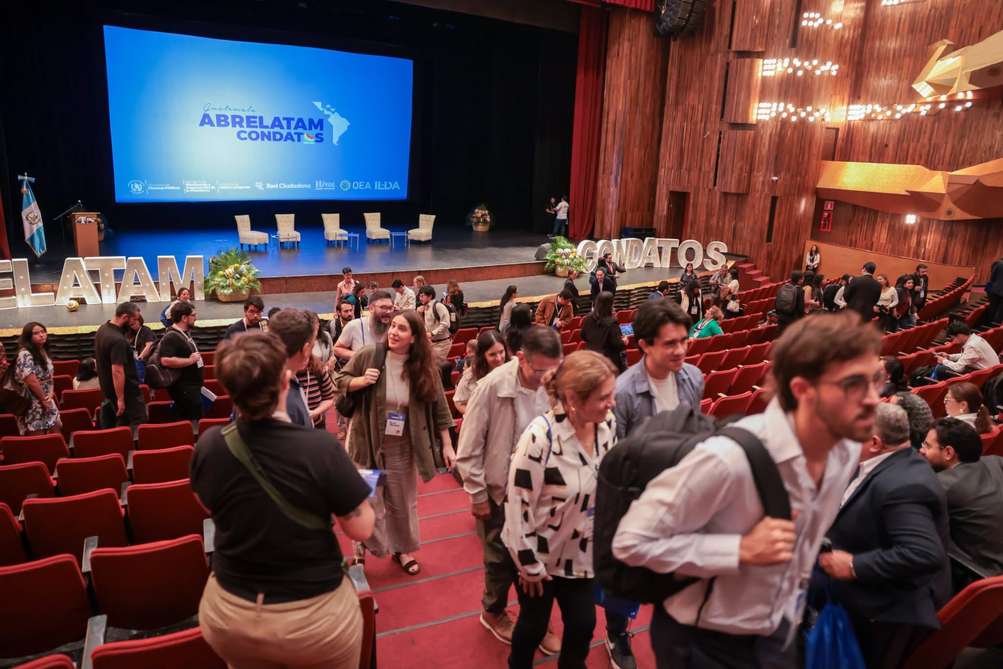 Tres ponentes participan en el evento AbreLatam ConDatos sobre el escenario de un teatro en Guatemala. (Ministerio de Finanzas de Guatemala)
