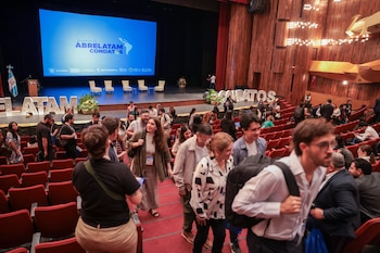 Tres personas hablan sentadas en sillones blancos en un escenario frente a una pantalla azul con la inscripción Guatemala AbreLatam ConDatos