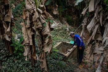Franklin Cáceres comprueba una bomba de agua utilizada para recolectar agua en un pozo en el vecindario de Petare, en Caracas, Venezuela, el 20 de marzo de 2023. Cáceres suministra agua a más de 400 personas en la parte alta de Petare. (AP Foto/Matías Delacroix)