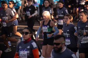 Un grupo de personas con ropa deportiva y dorsales numerados en el pecho corre por una calle asfaltada