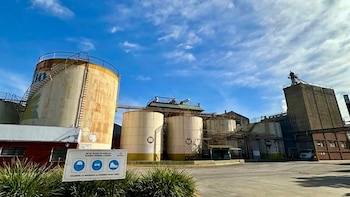 Tanques de almacenamiento industrial, edificios y un cartel de seguridad con pictogramas bajo un cielo despejado