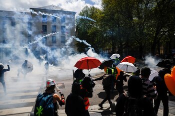 Demonstrators protect themselves with umbrellas