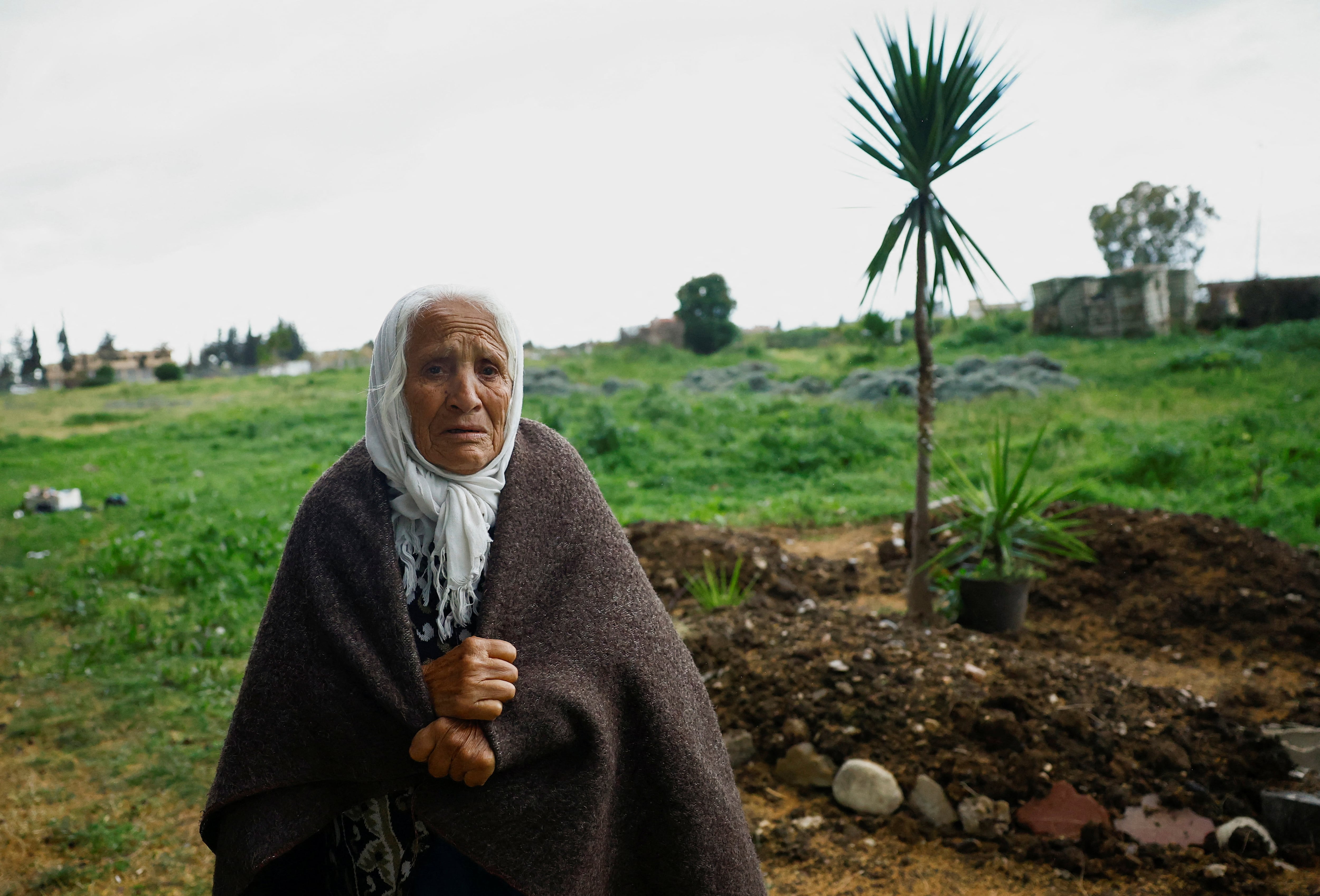Umm Haytham, una anciana alauita, se encuentra cerca de una tumba que contiene a una familia de tres alauitas enterrados en la base aérea de Hmeimim. (REUTERS)