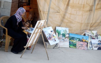 Khadeeja Bisharat, una artista palestina, pinta una obra inspirada en el conflicto palestino israelí mientras su hija Menas la observa, en el Valle del Jordán en la Cisjordania ocupada por Israel. 18 de junio, 2020. REUTERS/Raneen Sawafta