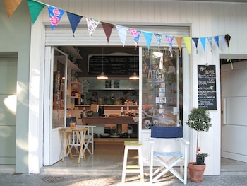 Entrada de un local gastronómico con guirnalda de banderines multicolores, pizarras de menú, una silla plegable blanca y mesas pequeñas