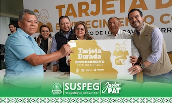 Un grupo de seis personas sonrientes en una ceremonia; un hombre de camisa azul entrega una tarjeta, y sostienen un gran cartel dorado de 'Tarjeta Dorada'