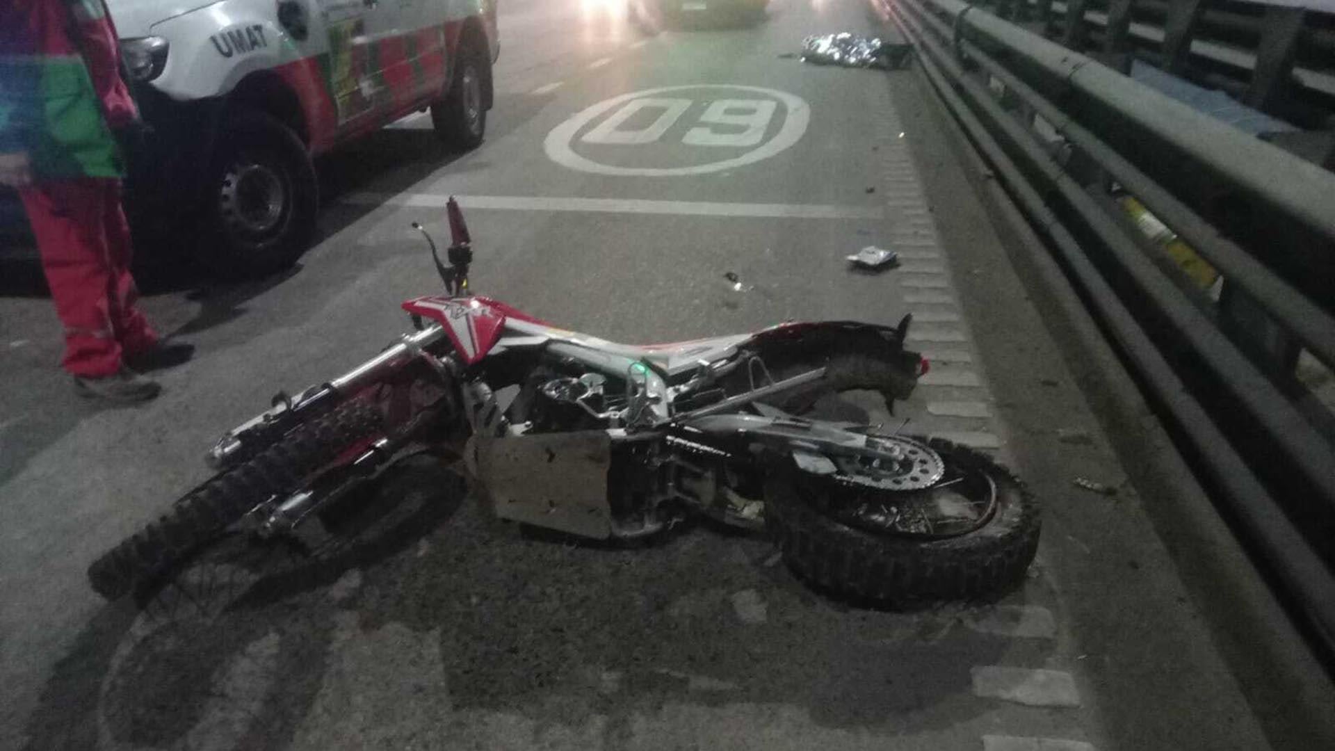 La imagen muestra una motocicleta caída en la Avenida 9 de Julio tras un accidente, con personal de emergencia y un vehículo de UMAT en el lugar.
