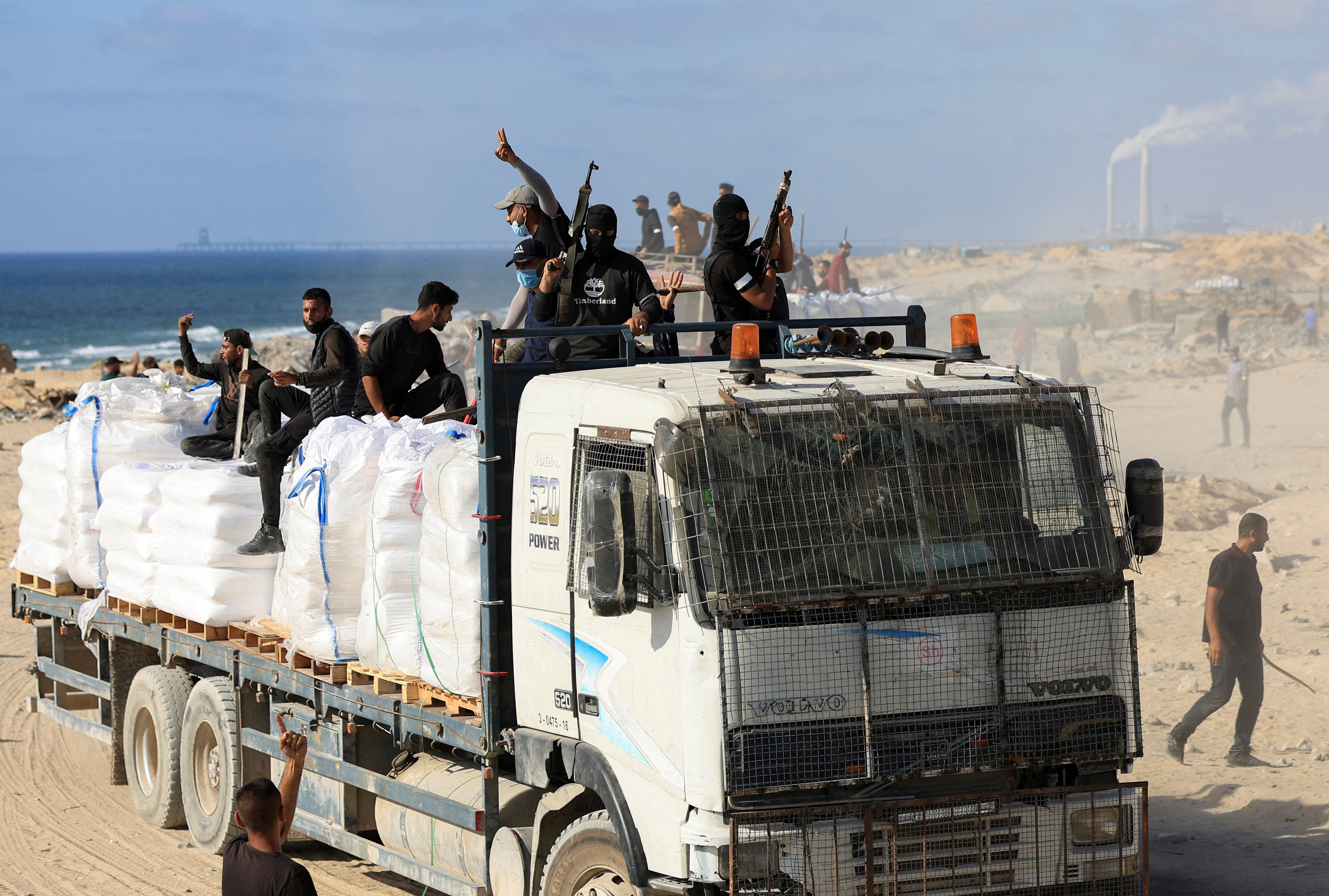 Miembros de grupos armados palestinos empuñan armas de fuego y armas blancas para proteger camiones de ayuda humanitaria en Beit Lahia, en el norte de la Franja de Gaza, el 25 de junio de 2025 (REUTERS/Dawoud Abu Alkas/Foto de archivo)