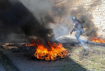 Un agente de la policía retira unas barricadas de neumáticos en llamas colocadas por residentes para evitar que los miembros de pandillas ingresen a su vecindario de Puerto Príncipe, Haití, el martes 19 de noviembre de 2024. (AP Foto/Odelyn Joseph)