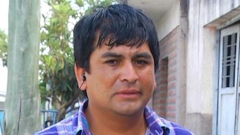 Primer plano de Javier Wayar, un hombre con cabello oscuro y camisa a cuadros, con un auricular negro en la oreja izquierda, en un entorno exterior