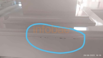 Detalle de una estructura de madera pintada de blanco con pequeñas marcas oscuras en el borde, encerradas por un círculo azul