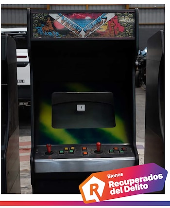 Máquina arcade negra con dos palancas rojas, botones, pantalla apagada con el número uno y sello de bienes recuperados del delito