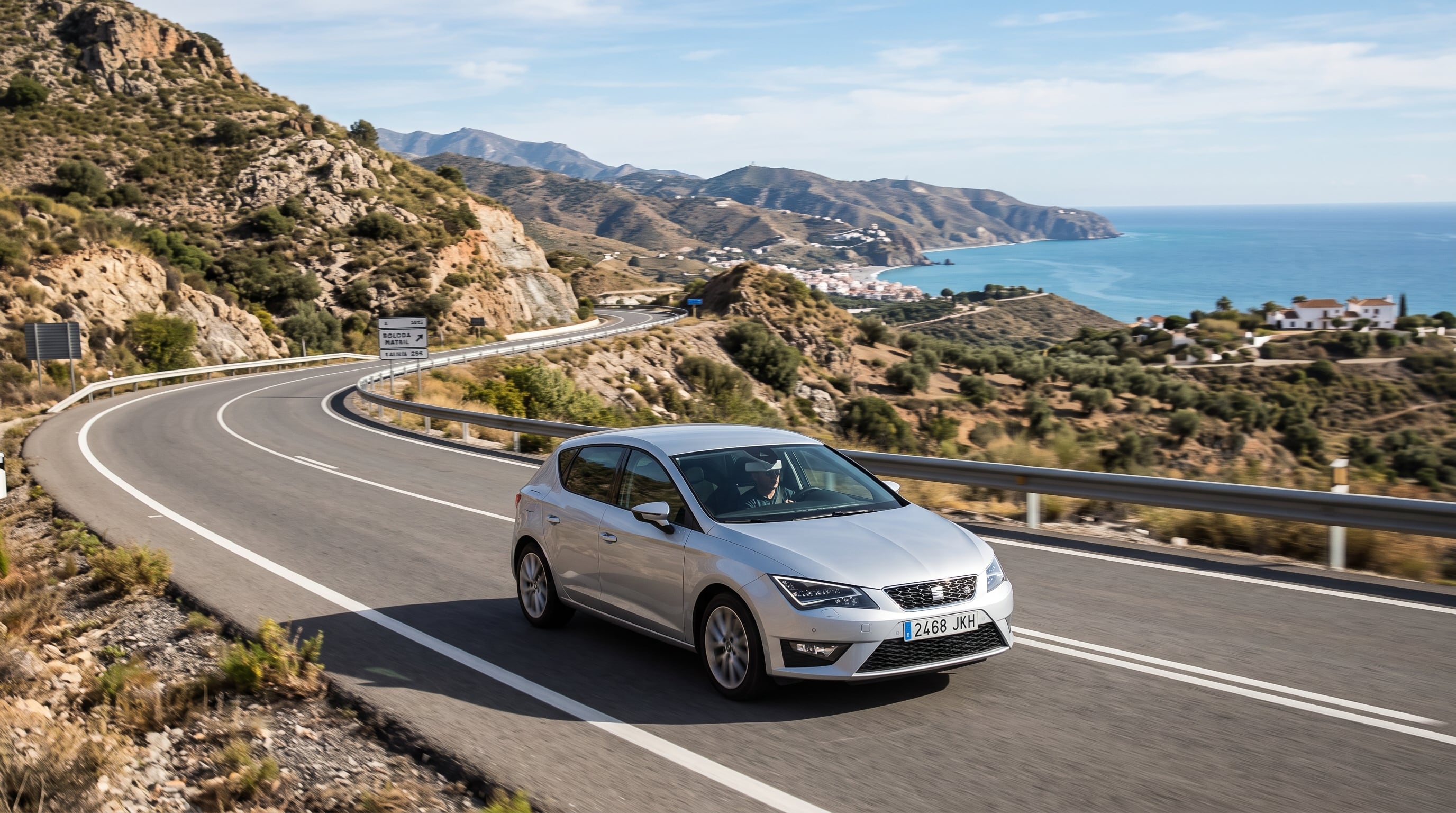 Un automóvil Seat de color gris transita por una carretera de montaña junto al mar en el litoral de España. (Imagen Ilustrativa Infobae)