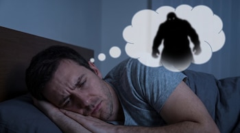 Un hombre duerme de lado con expresión preocupada. Una burbuja de pensamiento sobre su cabeza contiene la silueta oscura y borrosa de una figura grande y amenazante.