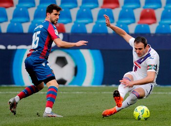 El defensa del Levante Sergio Postigo (i) lucha por el balón con el delantero del Eibar Kike García (d) durante un partido. EFE/Juan Carlos Cárdenas/Archivo