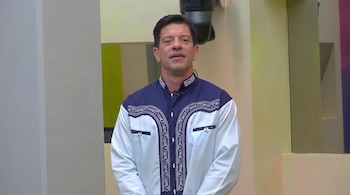 El cantante Yahir viste una camisa azul y blanca con bordados tradicionales frente a una cámara en un foro de televisión.