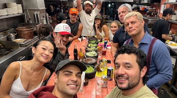 Nueve personas posan alrededor de una barra con recipientes de molcajete llenos de salsa, guacamole, latas de cerveza y refrescos.
