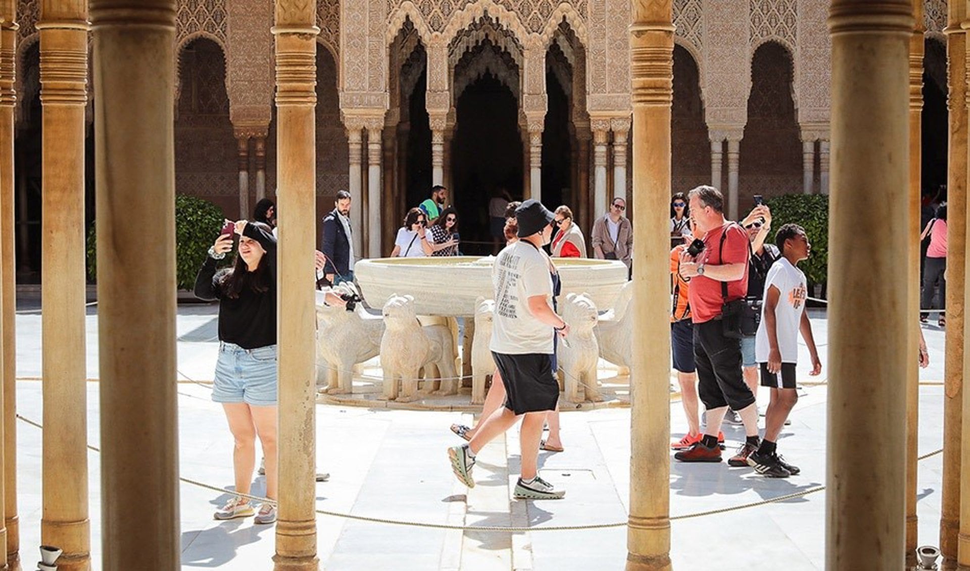 Turistas pasean por el patio de los leones de la Alhambra de Granada.